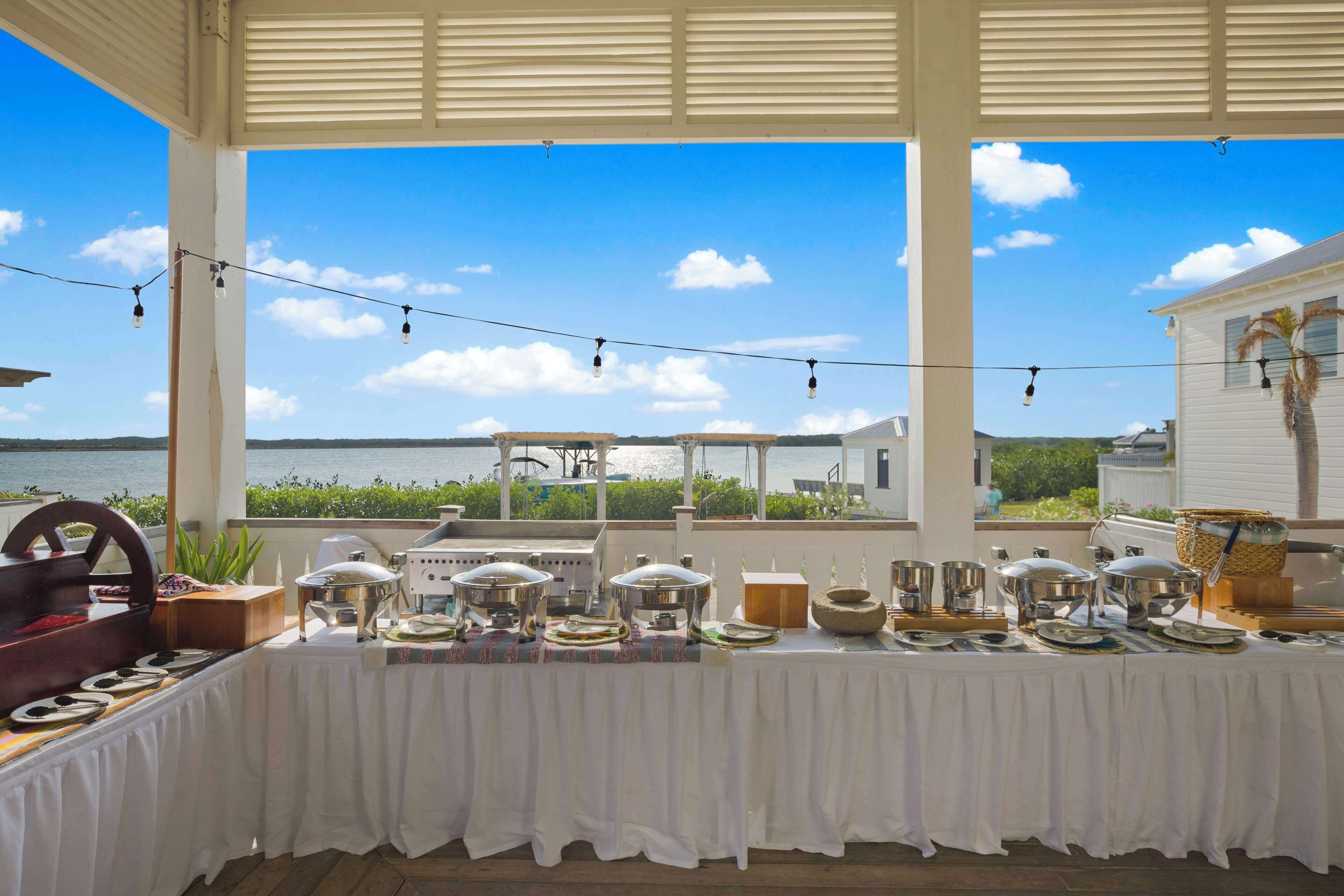 A buffet table set up on a covered patio with a view of the sea.