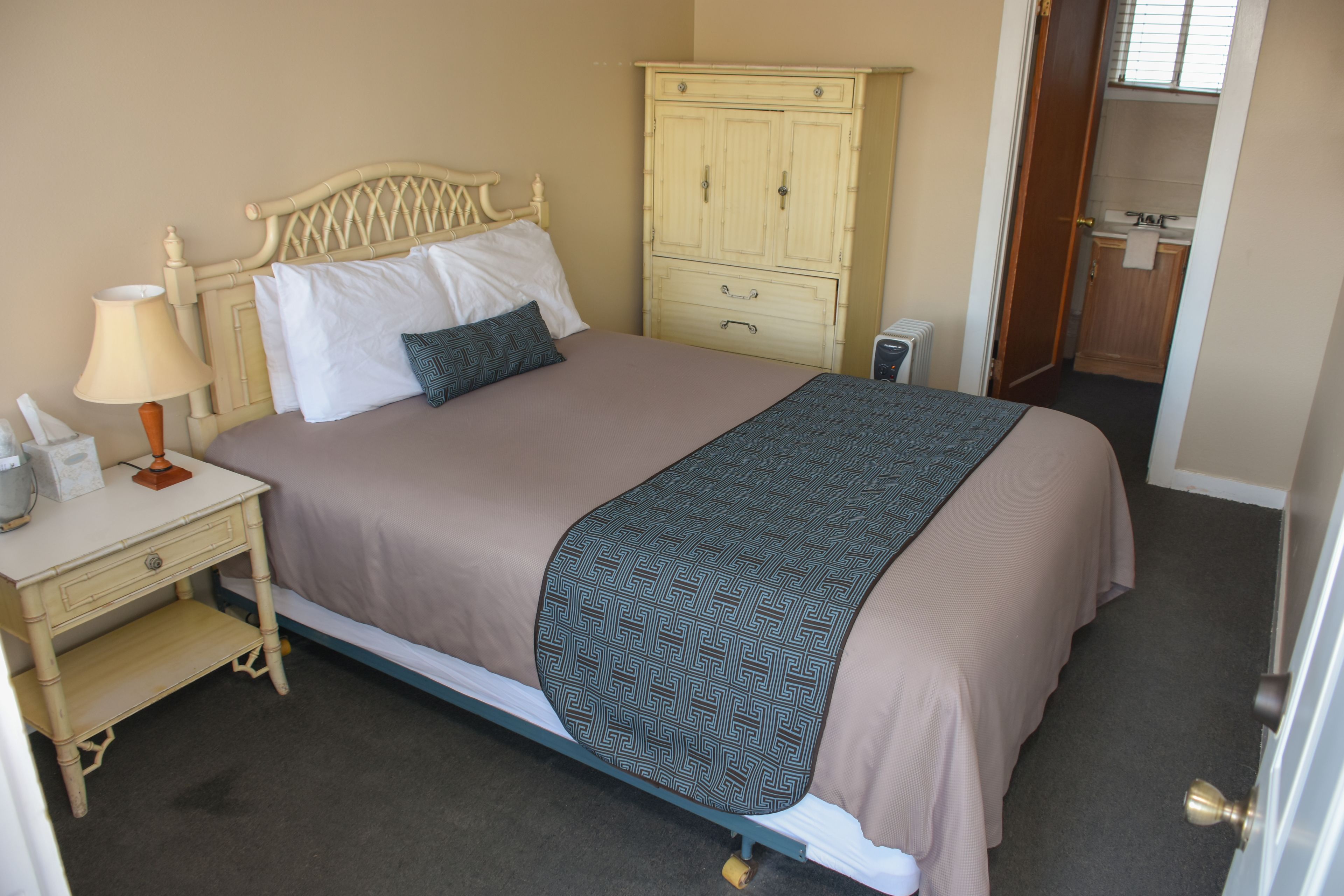 Une chambre à coucher avec un lit, une table de chevet, une lampe et une armoire.