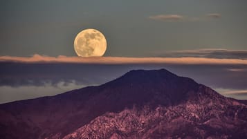 A mountain with a full moon in the sky.