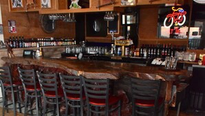A bar area with wooden furniture, a round table with a beer mug, and a neon bicycle sign. - Panamint Springs Resort (Panamint Springs)