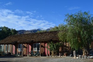 A rustic wooden building with a sloped roof, multiple windows, and a red door.