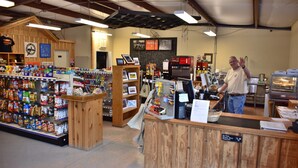 A store interior with a wooden counter, shelves stocked with snacks, and a Coca-Cola refrigerator. - Panamint Springs Resort (Panamint Springs)