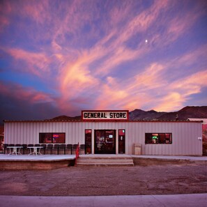 A building labeled "GENERAL STORE" with a flat roof, a front entrance, and a small outdoor seating area with tables and chairs. - Panamint Springs Resort (Panamint Springs)
