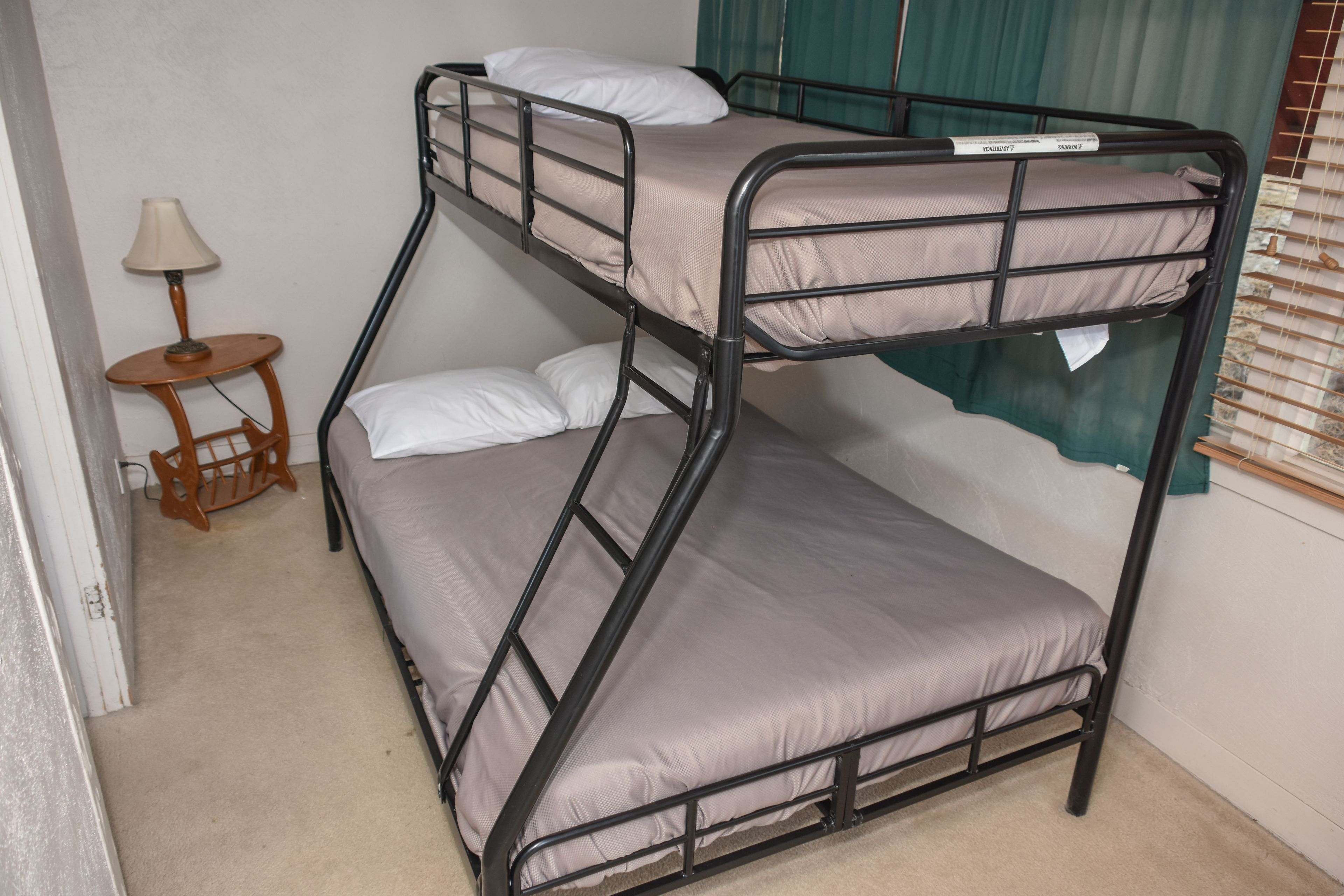 A bunk bed with a small table and lamp beside it.