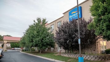 Edificio del Baymont Inn & Suites con techo rojo, rodeado de árboles y un estacionamiento.