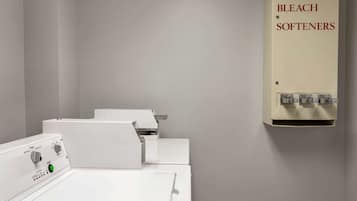 A laundry room with a white washing machine, a dryer, and a wall-mounted soap, bleach, and softener dispenser.