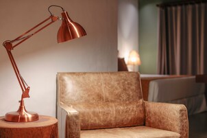 Un sillón de cuero con una mesita de madera y una lámpara de escritorio de cobre.