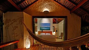 A hammock on a wooden deck with a view of a bedroom and a painting of a beach. - Pousada Samba Pa Ti (Porto de Pedras)