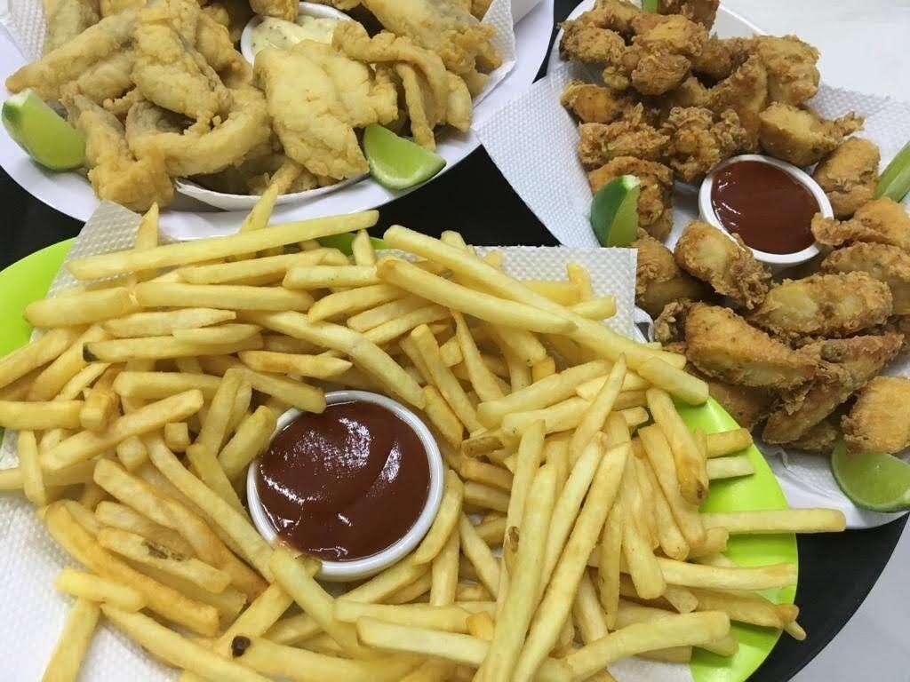 Un plato de papas fritas con kétchup, aros de cebolla y pollo frito.
