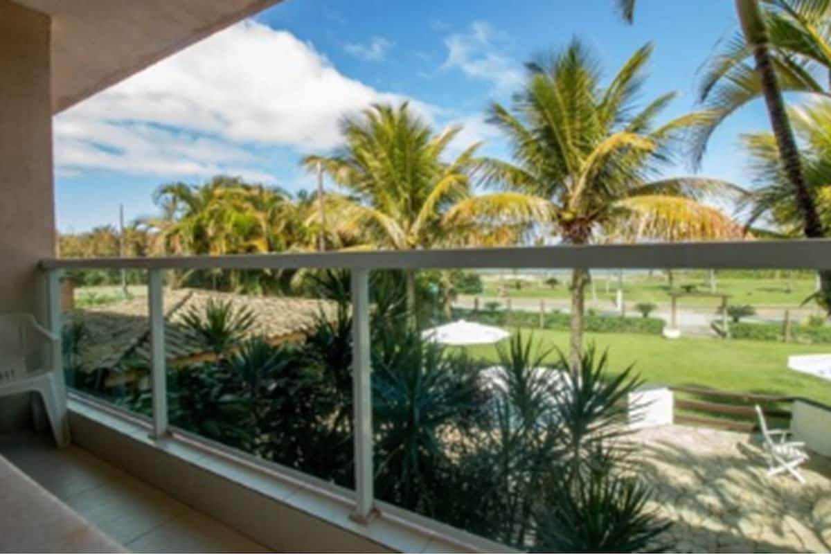 Un balcón con vistas a un jardín tropical, con palmeras y césped.