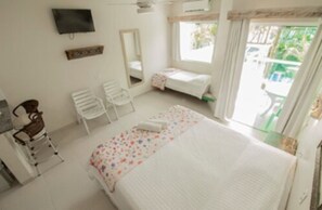 A bedroom with a bed, a chair, a TV, and a window. - Apart Hotel Porto Kanoas (Bertioga)