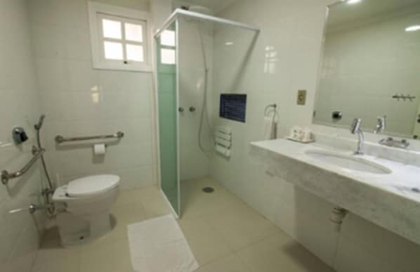 A bathroom with a toilet, a shower, a sink, and a mirror. - Apart Hotel Porto Kanoas (Bertioga)