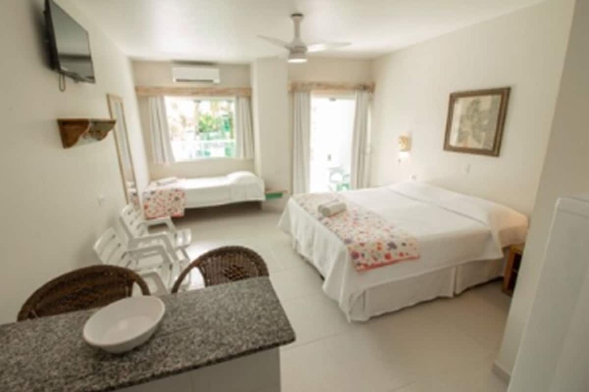 Un dormitorio con una cama, un escritorio, una silla, un televisor y una ventana.