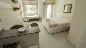Een hotelkamer met een bed, een klein bureau met stoel, een televisie en een raam met gordijnen.