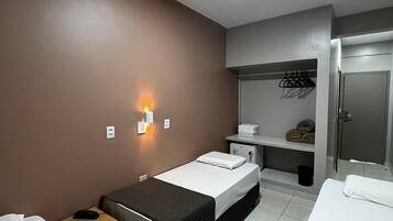Habitación de hotel con dos camas, un escritorio, un armario y baño.