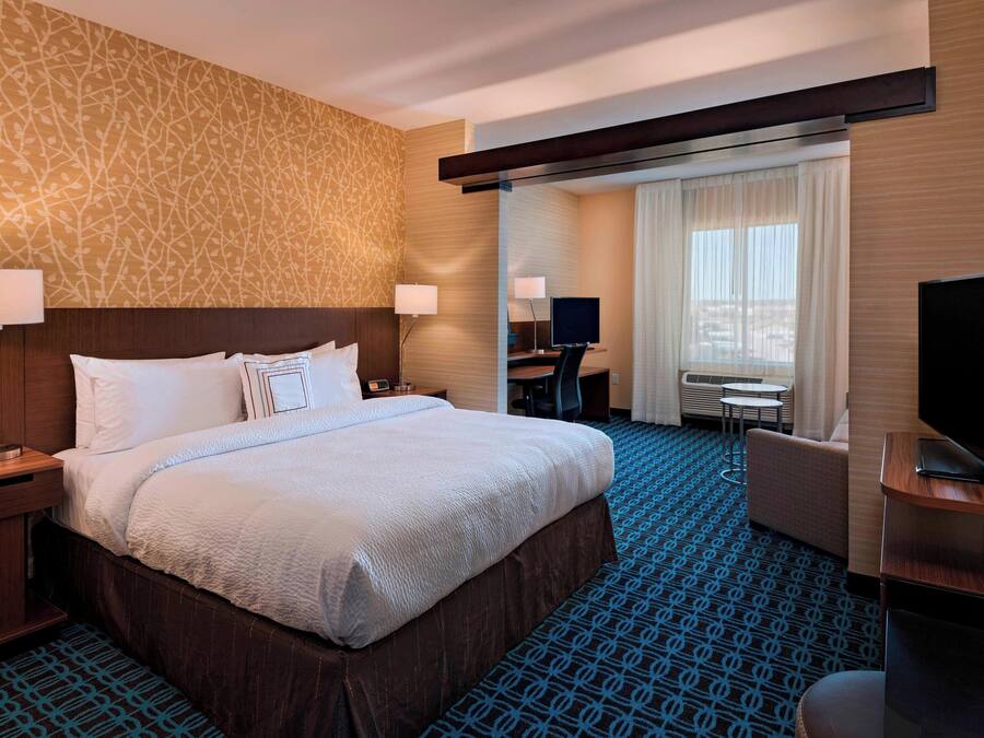 Ein Hotelzimmer mit einem großen Bett, einem Schreibtisch, einem Fernseher und Blick auf die Stadt durch das Fenster.
