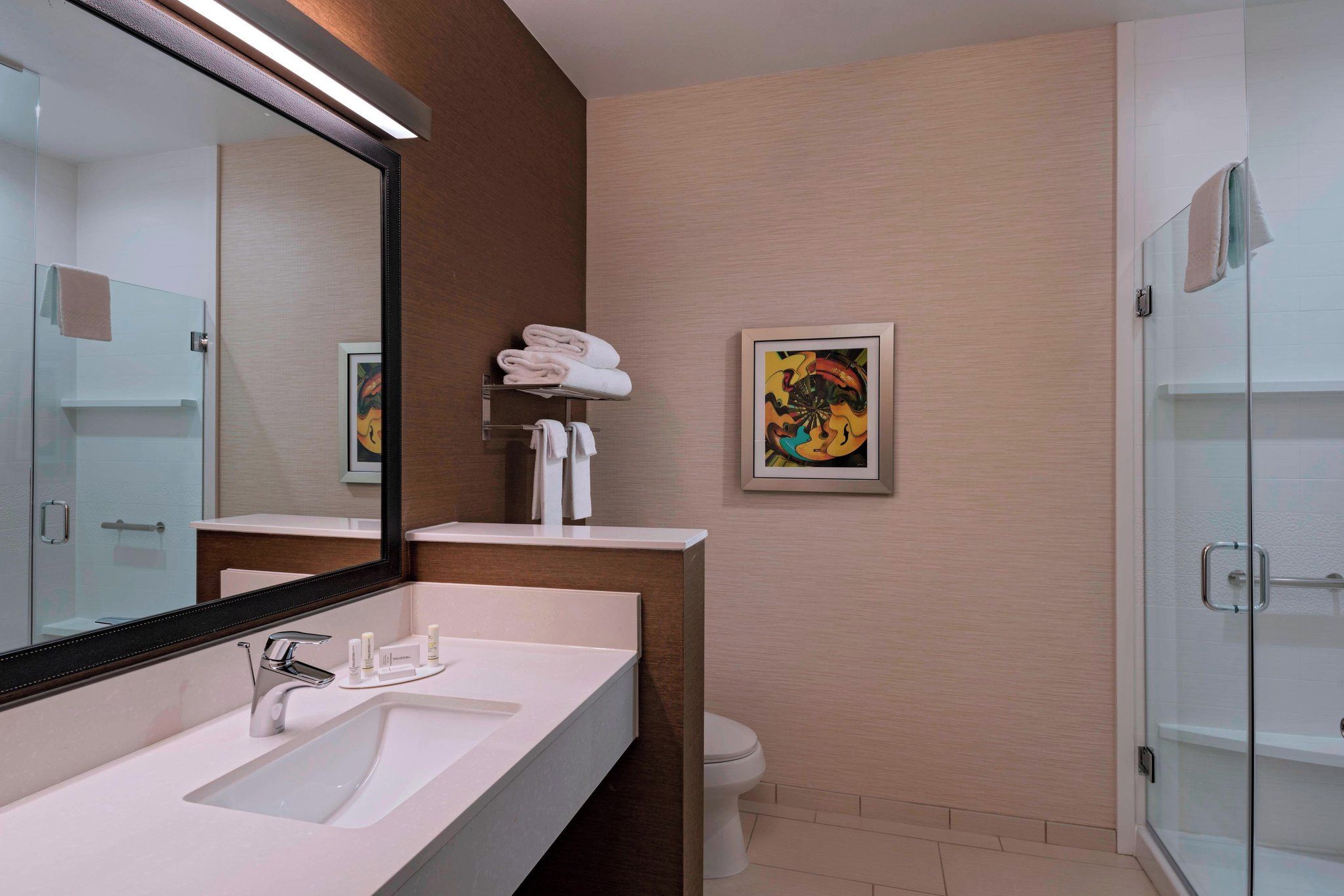 Un baño moderno con un espejo grande, un lavabo, un inodoro y una zona de ducha.