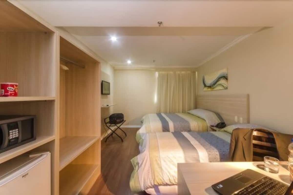 Ein Hotelzimmer mit einem Bett, einem Schreibtisch, einem Laptop, einer Mikrowelle und einem Kühlschrank.