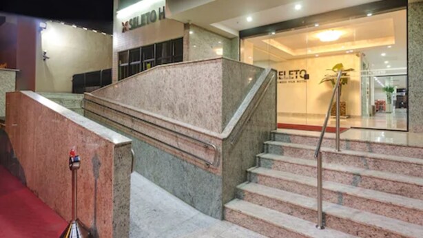 A hotel interior with a marble staircase, a reception desk, and a glass door entrance. - Seleto Hotel (Volta Redonda)