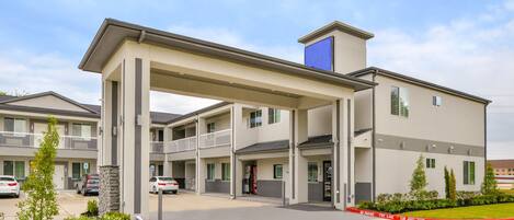 A multi-story motel with a covered entrance, a parking lot, and a fire lane.