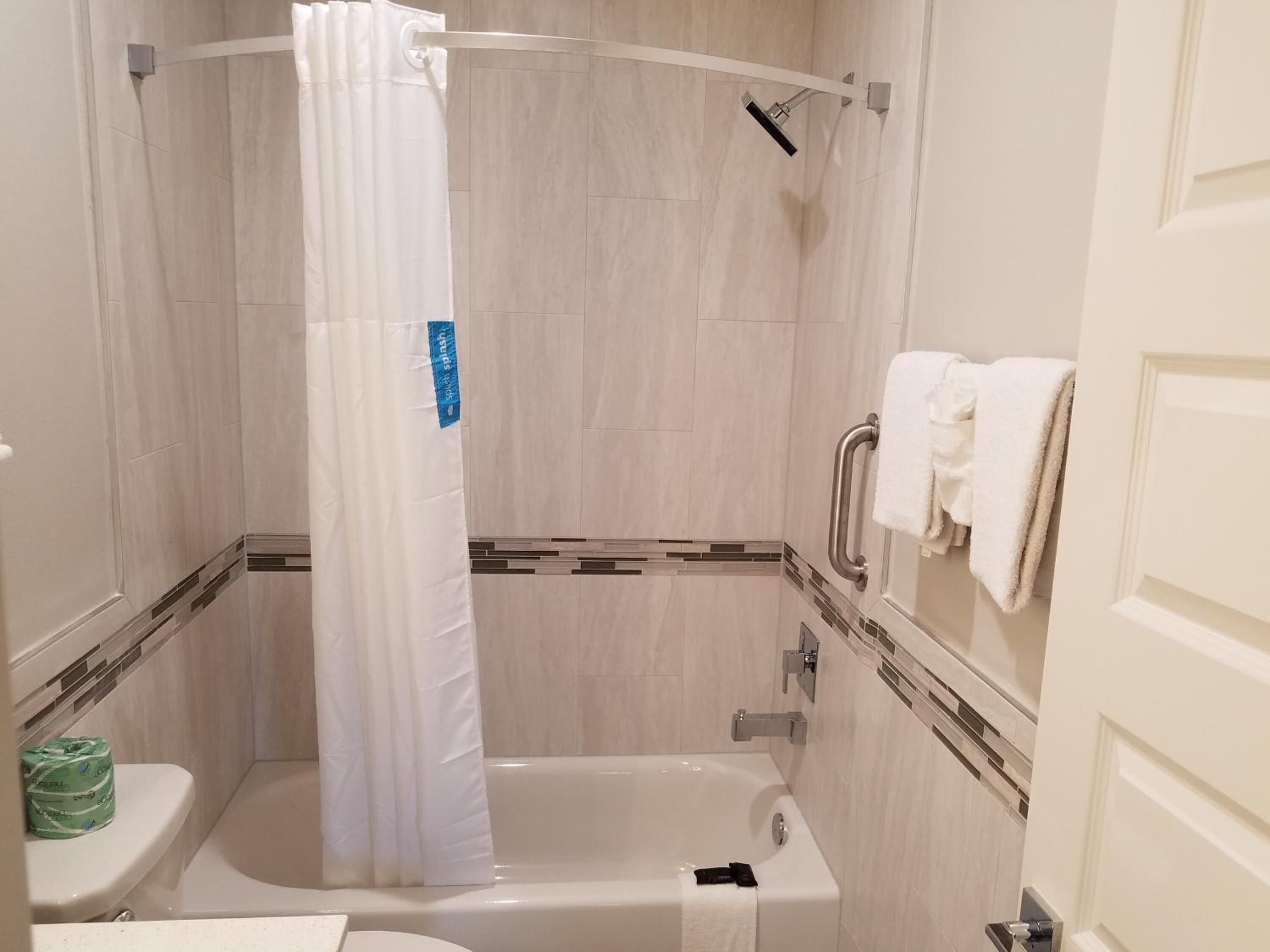 A bathroom with a shower, toilet, and bathtub.