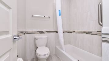 Un baño con inodoro, bañera y cortina de ducha.