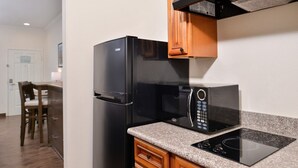 A kitchen with a black refrigerator, a microwave, and an induction cooktop. - Crystal Inn & Suites IAH Humble (Humble)