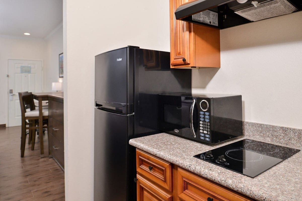 A kitchen with a black refrigerator, a microwave, and an induction cooktop.