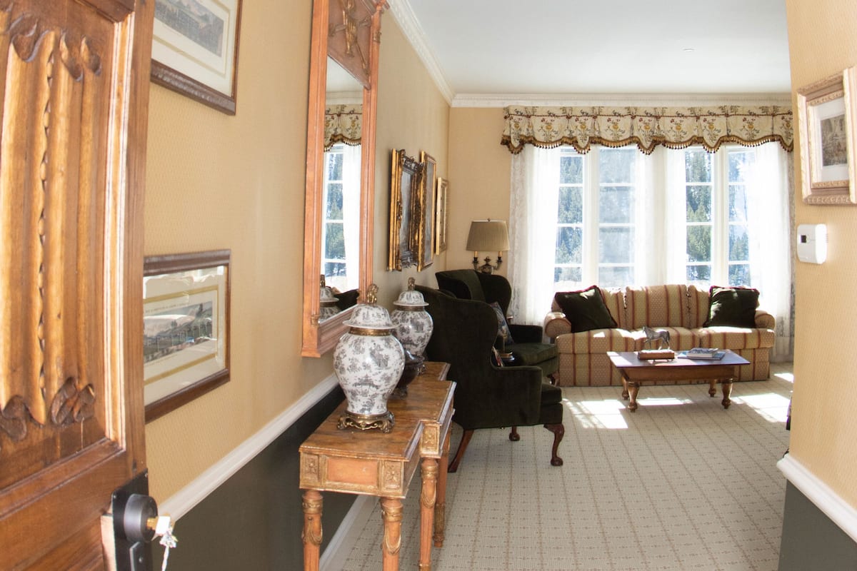 A hallway leading to a living room with a chandelier, a sofa, and a coffee table.