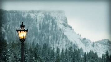 A street lamp in a snowy landscape with a mountain in the background.