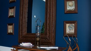 Una habitación con pared azul, un espejo grande y cuadros enmarcados.