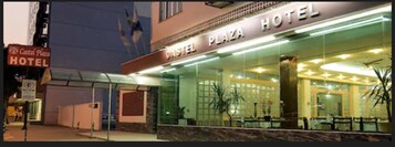 Exterior del hotel Castel Plaza, con fachada de vidrio, zona de estar al aire libre y un cartel.
