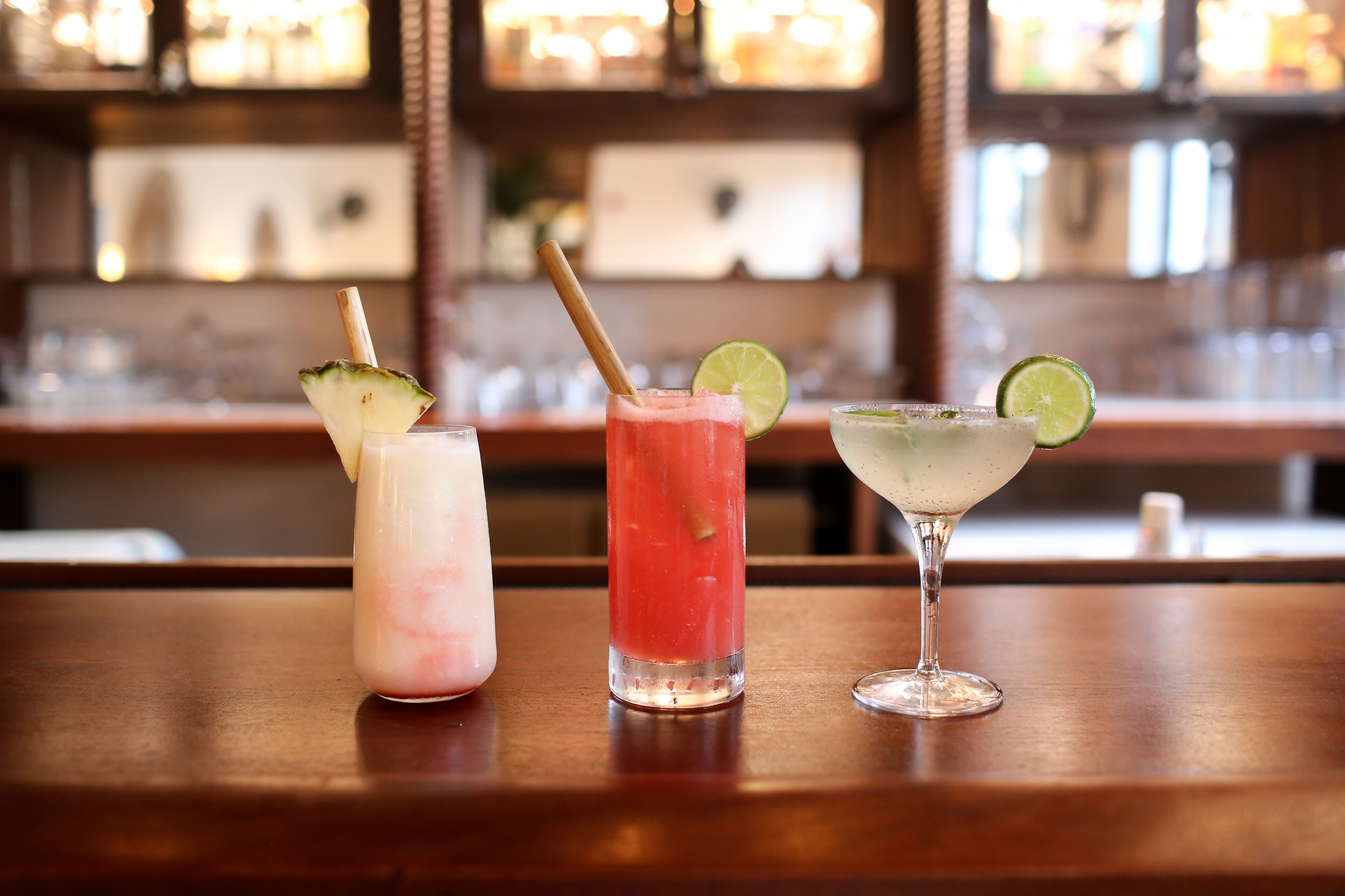 Three drinks on a bar counter with a blurred background of a bar.