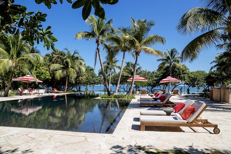 Una piscina al aire libre, sombrillas, sillones reclinables de piscina