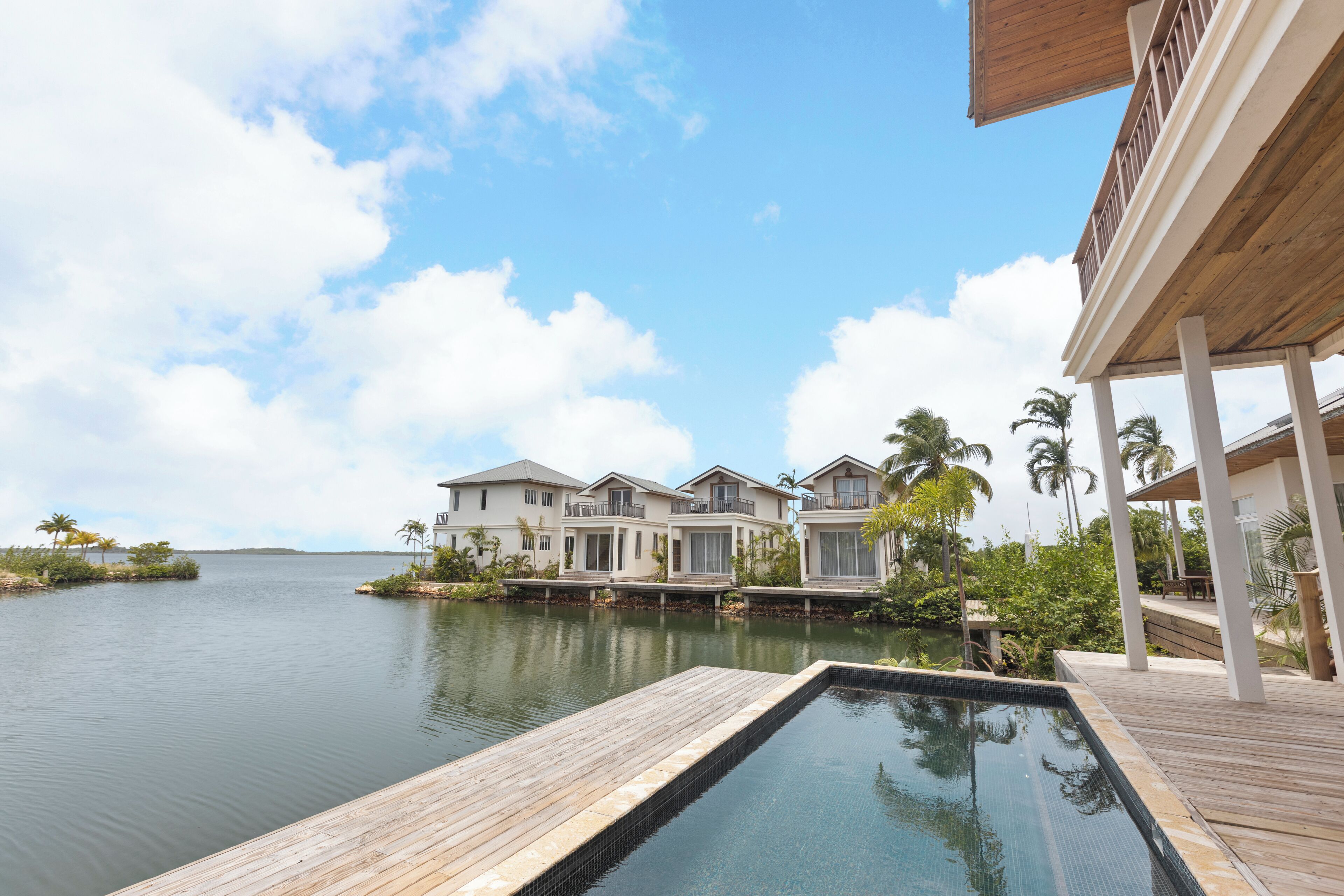 A waterfront property with a swimming pool, wooden deck, and multiple houses with balconies.