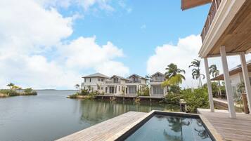 A waterfront property with a swimming pool, wooden deck, and multiple houses with balconies.