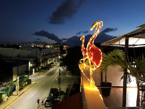A balcony with a view of a street at night, featuring a decorative flamingo sculpture.