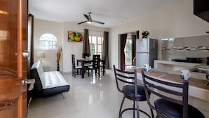 A modern kitchen with a refrigerator, stove, and dining area with chairs and a table. - Posada Flamingos (Playa del Carmen)