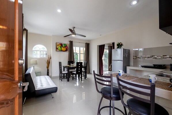 A modern kitchen with a refrigerator, stove, and dining area with chairs and a table.