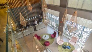 Een ruime lobby met een hoge plafond, moderne zitgelegenheid en grote ramen voor natuurlijk licht.