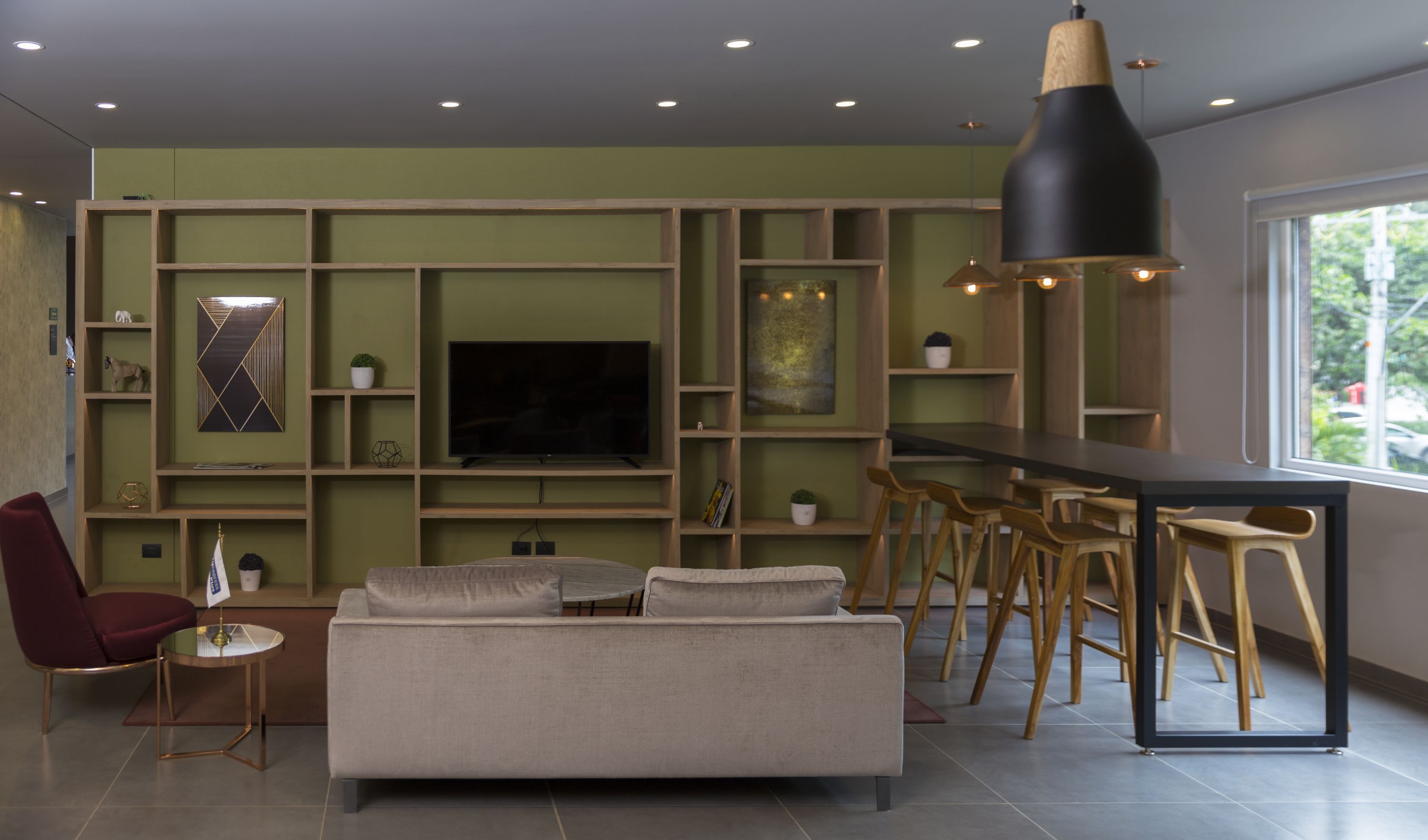 A modern living room with a sofa, a TV, and a bar area with stools.