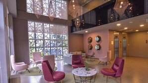 Een ruime lobby met moderne zitplaatsen, grote ramen en decoratieve verlichting.