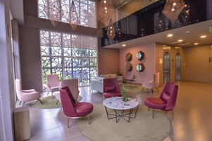 Um hall amplo com assentos modernos, grandes janelas e iluminação decorativa.