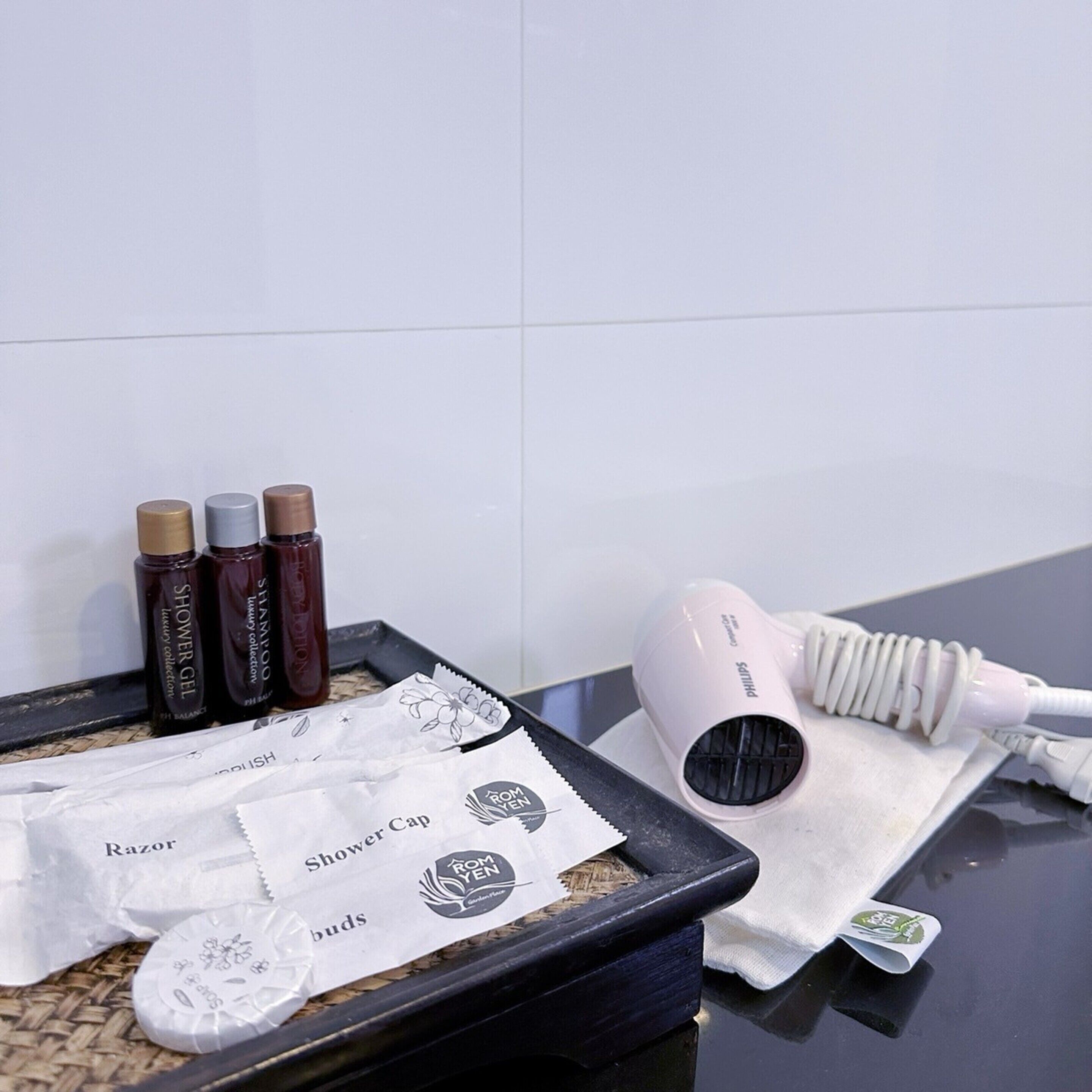Un lavamanos de baño con artículos de aseo personal, incluyendo un secador de pelo, gel de ducha y crema de afeitar.