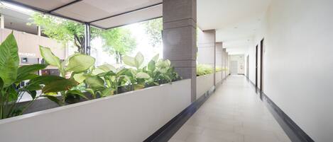 A corridor with a tiled floor, a planter with green plants, and a modern architectural design.