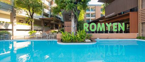 A swimming pool with a sign reading "ROMYEN" in the background.