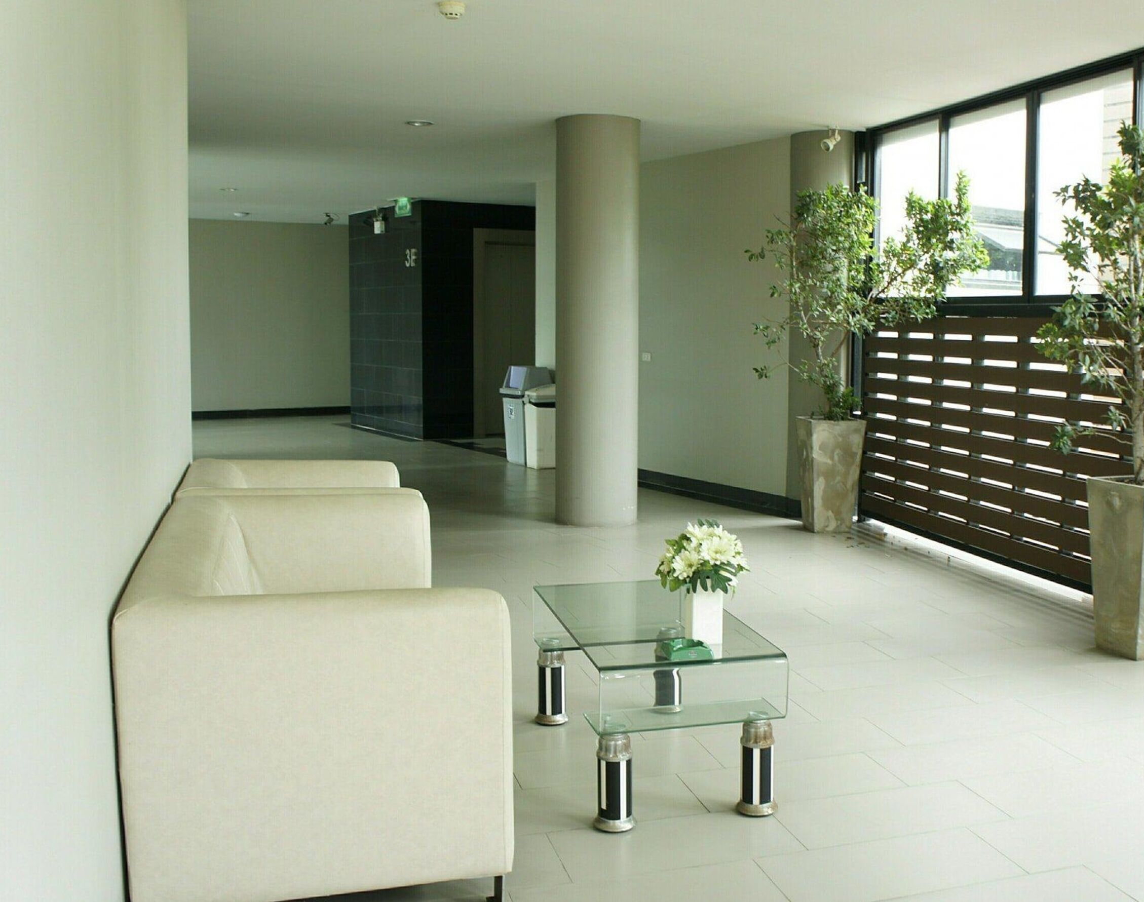 A modern lobby with a seating area, a glass coffee table, and a potted plant.