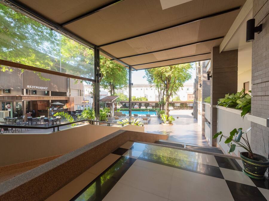 Un espacio interior moderno con vista a una piscina, asientos exteriores y una escalera que baja a un nivel inferior.