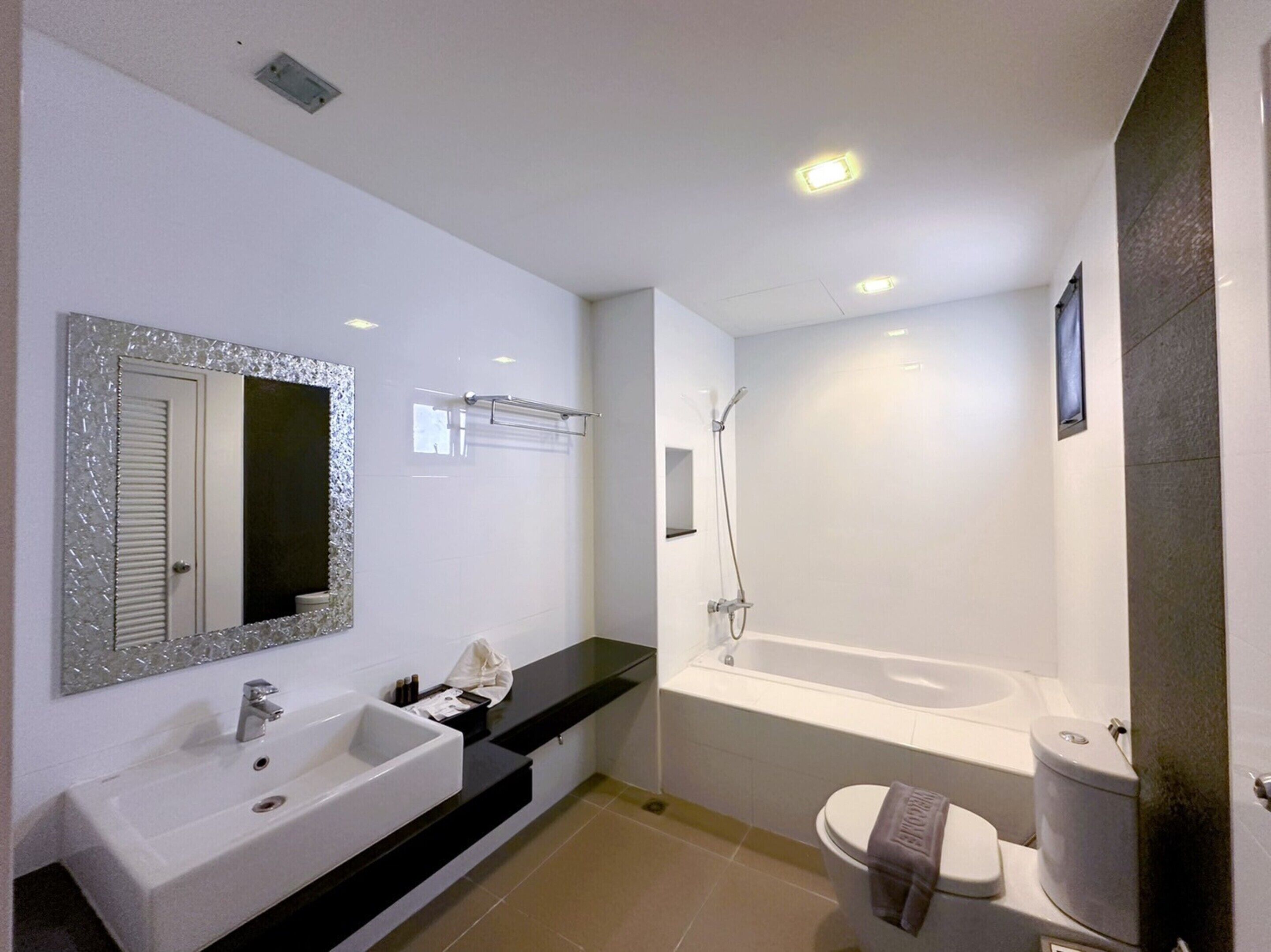 A modern bathroom with a white sink, mirror, and bathtub.