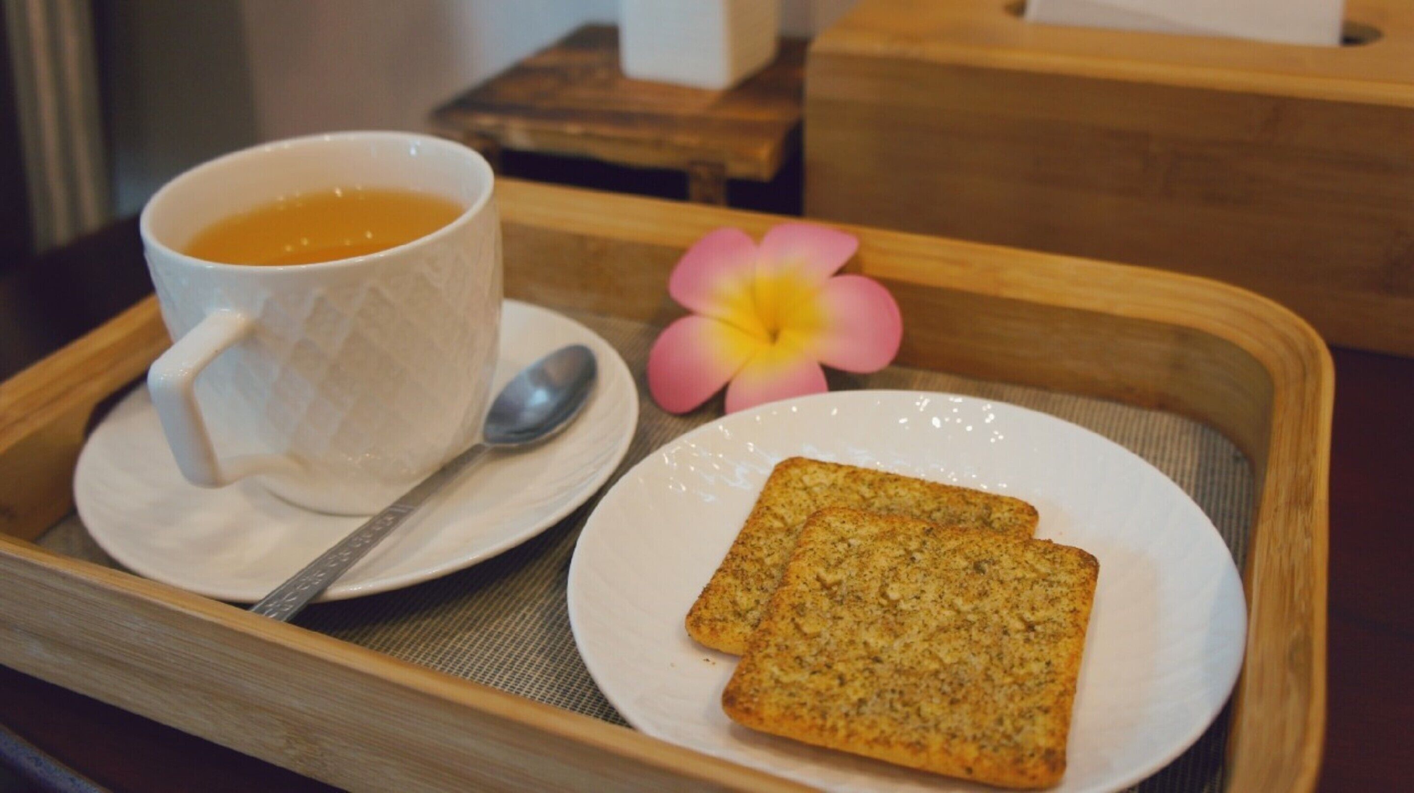Un plateau avec une tasse de thé, une cuillère et deux tranches de pain grillé, posé sur une table.